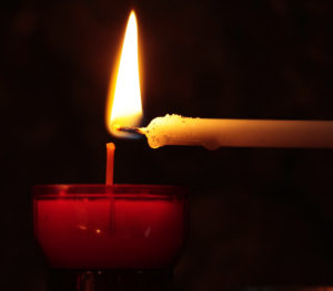 a taper candle lighting a larger candle.