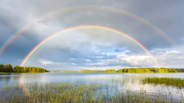 A double rainbow over a still lake.