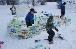 Kids building a rainbow ice wall in the snow, grinning and clearly having fun.