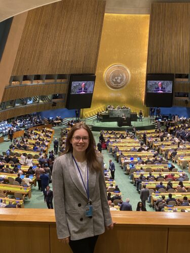 a white-presenting woman standing the UN assembly hall.